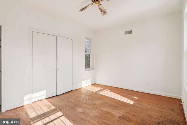 unfurnished bedroom featuring hardwood / wood-style flooring, ceiling fan, and a closet