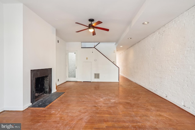 unfurnished living room with ceiling fan, brick wall, and concrete floors