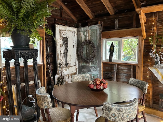 dining space featuring vaulted ceiling with beams, wooden walls, and wood ceiling