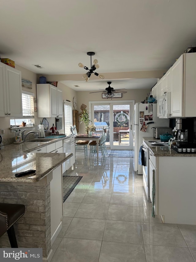 kitchen with white appliances, dark stone counters, ceiling fan, light tile patterned floors, and white cabinetry