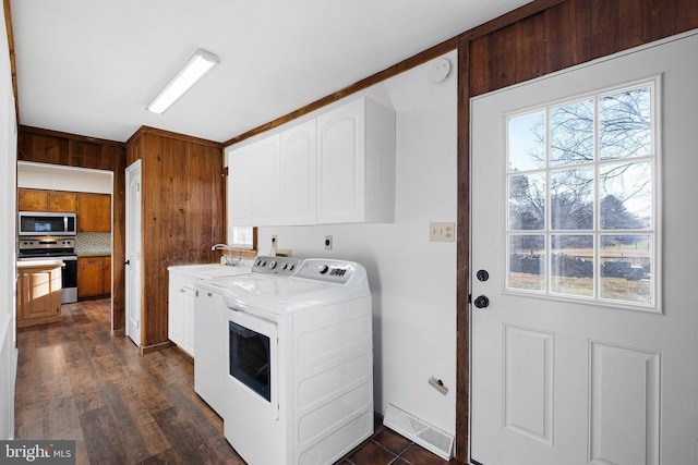 clothes washing area with sink, washer and dryer, cabinets, and dark wood-type flooring