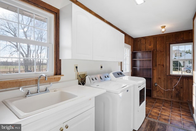 laundry room featuring washer and clothes dryer, wood walls, cabinets, sink, and dark hardwood / wood-style floors