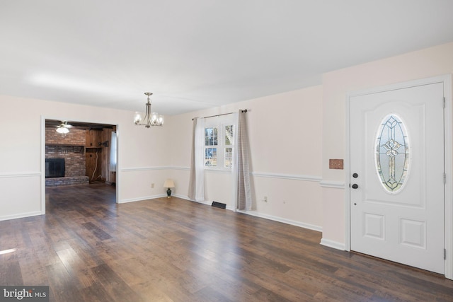 foyer with a fireplace, dark wood-type flooring, and a notable chandelier