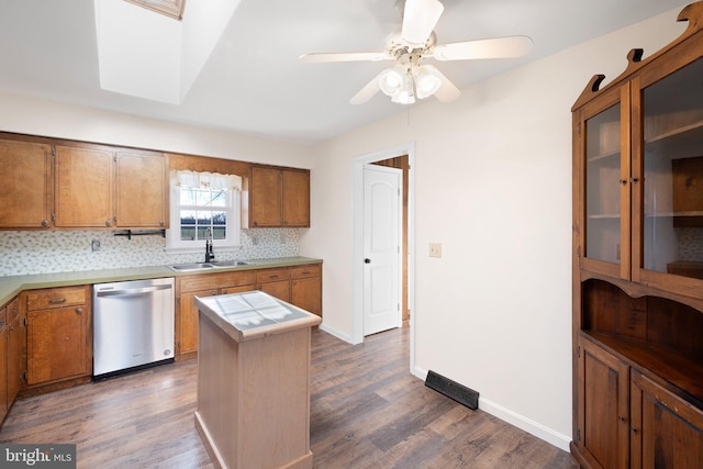 kitchen featuring dark wood-type flooring, sink, stainless steel dishwasher, tasteful backsplash, and a kitchen island