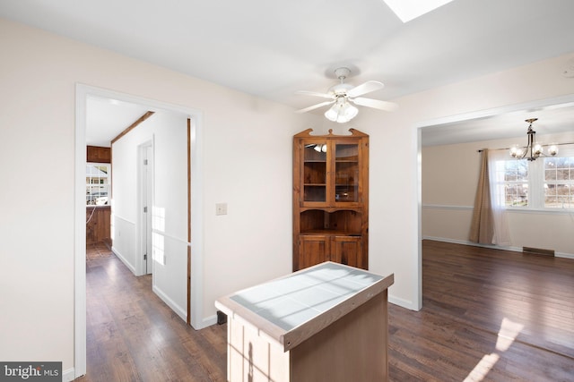 kitchen featuring dark hardwood / wood-style floors, tile countertops, pendant lighting, a kitchen island, and ceiling fan with notable chandelier