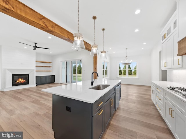 kitchen featuring pendant lighting, white cabinetry, a center island with sink, and a healthy amount of sunlight