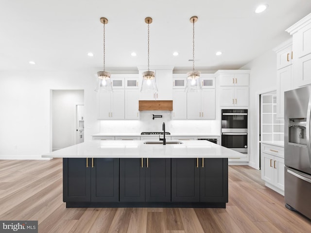 kitchen featuring white cabinetry, a large island, stainless steel appliances, and light wood-type flooring