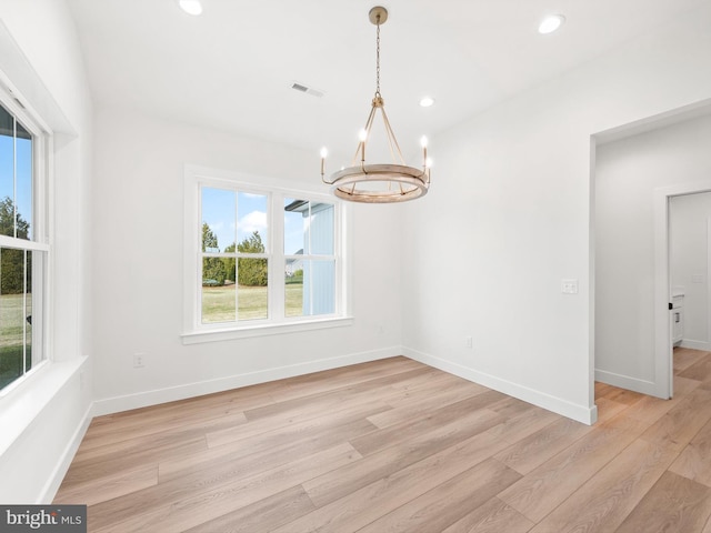 unfurnished dining area featuring light hardwood / wood-style floors and an inviting chandelier