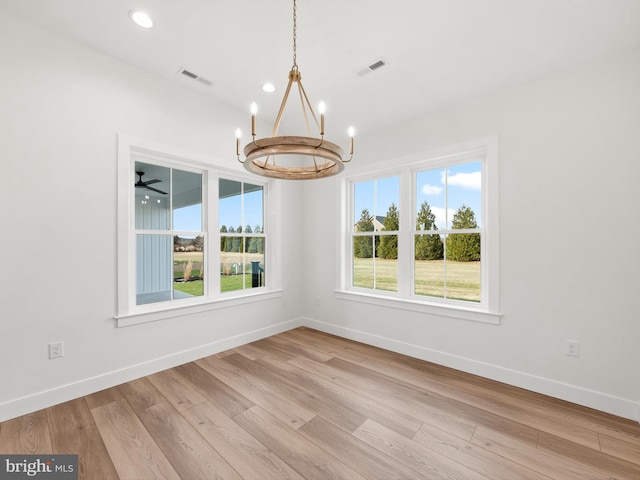 unfurnished dining area with ceiling fan with notable chandelier and light hardwood / wood-style floors