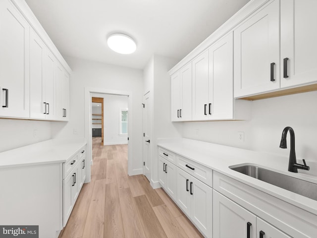 kitchen with white cabinets, light hardwood / wood-style floors, and sink