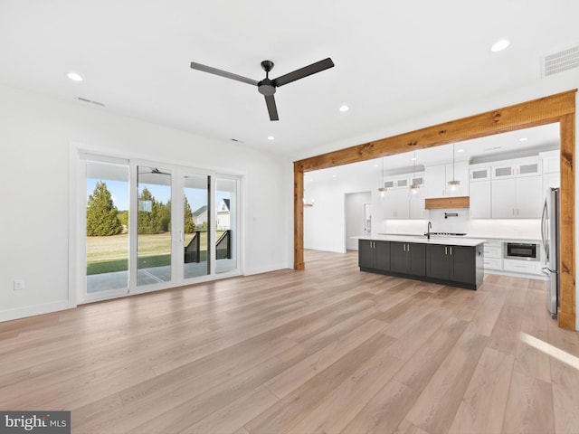 kitchen featuring a center island with sink, white cabinets, hanging light fixtures, ceiling fan, and light hardwood / wood-style floors