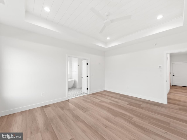 spare room featuring a tray ceiling, ceiling fan, and light hardwood / wood-style floors