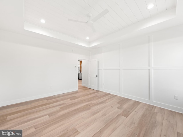 spare room featuring light hardwood / wood-style flooring, a raised ceiling, and ceiling fan