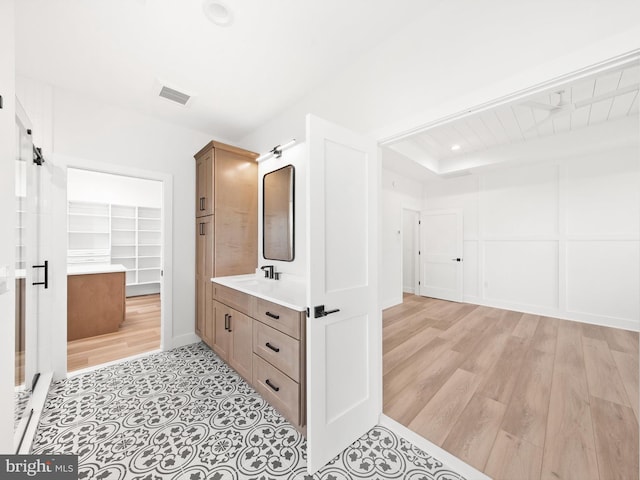 bathroom with hardwood / wood-style floors, vanity, and a tray ceiling