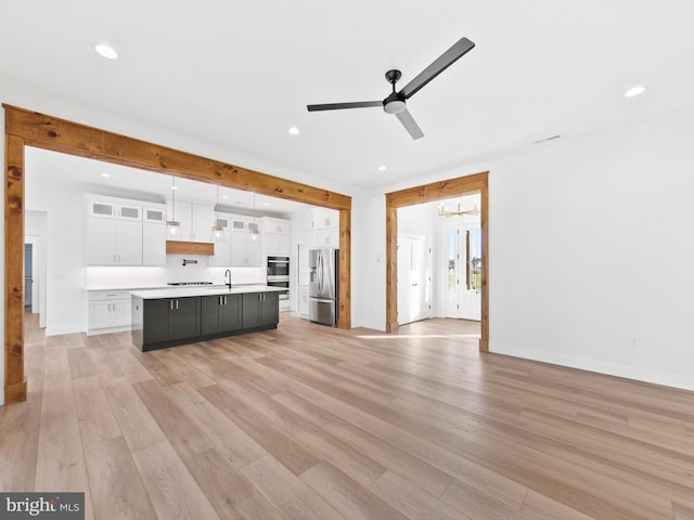 unfurnished living room with ceiling fan, sink, and light hardwood / wood-style flooring