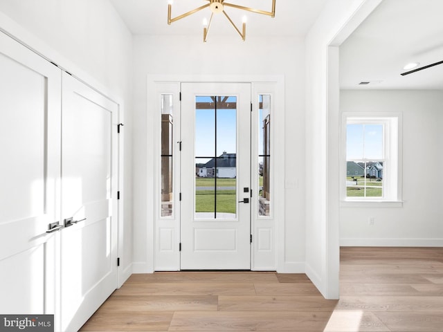 entrance foyer with light hardwood / wood-style floors and an inviting chandelier