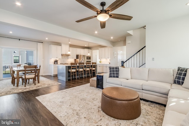 living room with ceiling fan and dark wood-type flooring