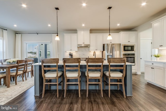 kitchen featuring pendant lighting, white cabinets, an island with sink, and appliances with stainless steel finishes