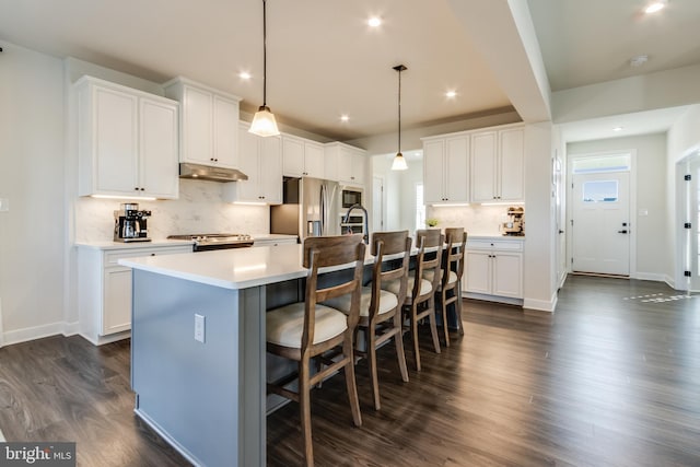 kitchen with white cabinets, an island with sink, stainless steel appliances, and decorative light fixtures