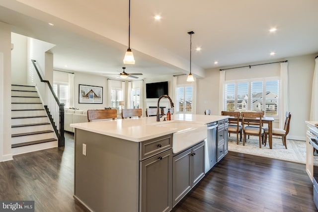 kitchen featuring gray cabinets, dark hardwood / wood-style flooring, an island with sink, and decorative light fixtures