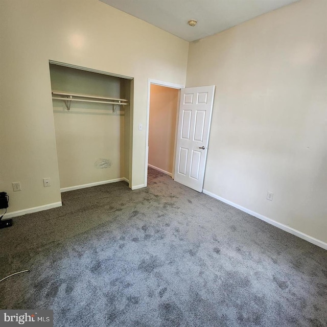 unfurnished bedroom with dark carpet and a closet