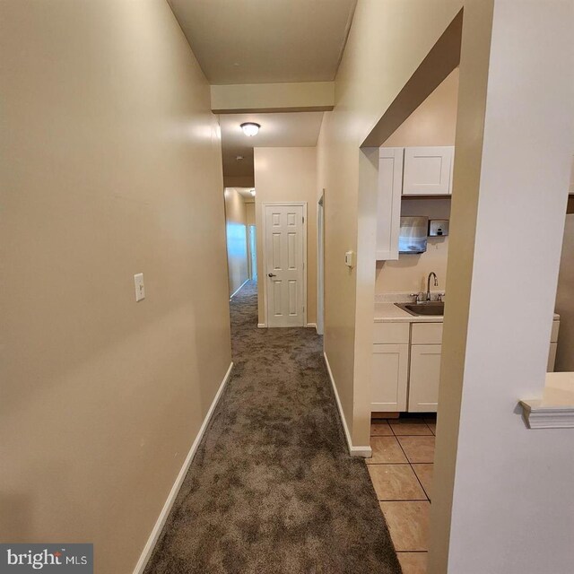 hallway featuring light colored carpet and sink