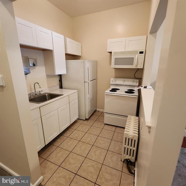 kitchen featuring radiator, white appliances, sink, light tile patterned floors, and white cabinetry