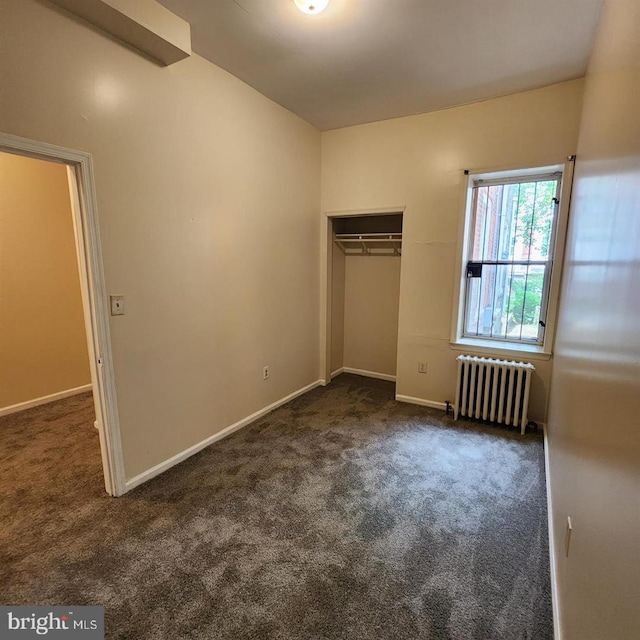 unfurnished bedroom with dark colored carpet, radiator heating unit, and a closet