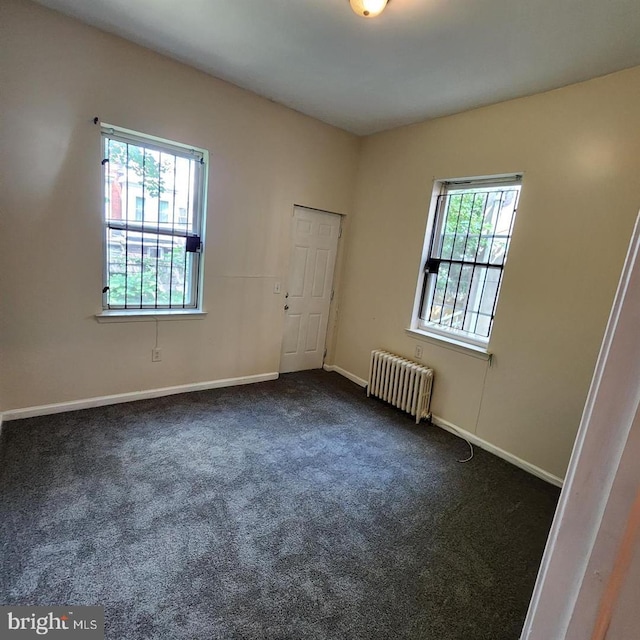 carpeted spare room with a healthy amount of sunlight and radiator heating unit