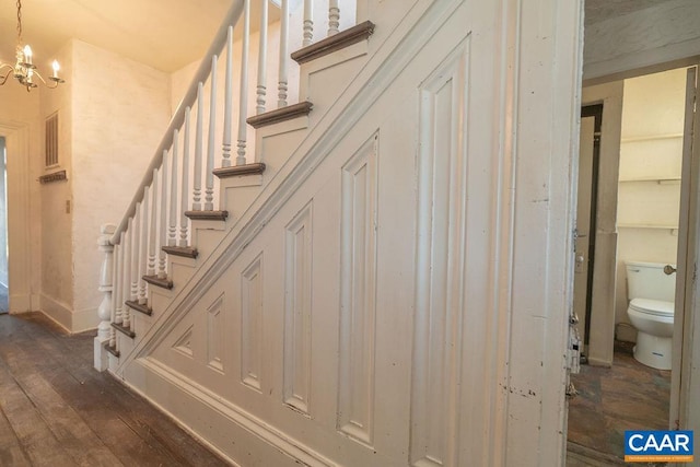 stairway featuring hardwood / wood-style floors and a chandelier