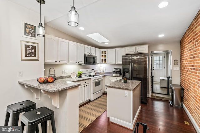 kitchen with white cabinets, stainless steel refrigerator with ice dispenser, decorative light fixtures, white range with gas stovetop, and brick wall