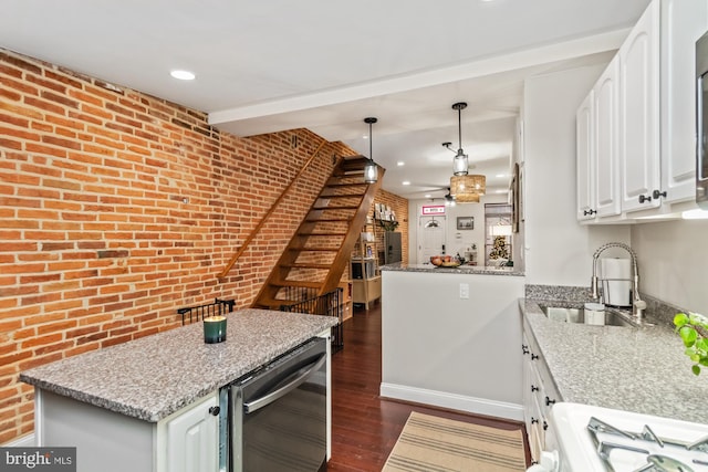 kitchen featuring kitchen peninsula, sink, dark hardwood / wood-style floors, and brick wall