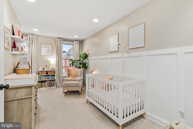 bedroom featuring light carpet and a crib