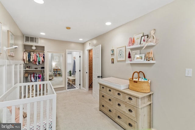 bedroom featuring light carpet and a crib