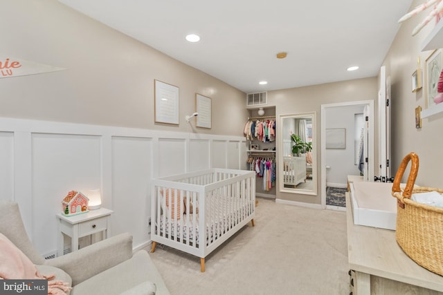 carpeted bedroom featuring ensuite bathroom and a nursery area