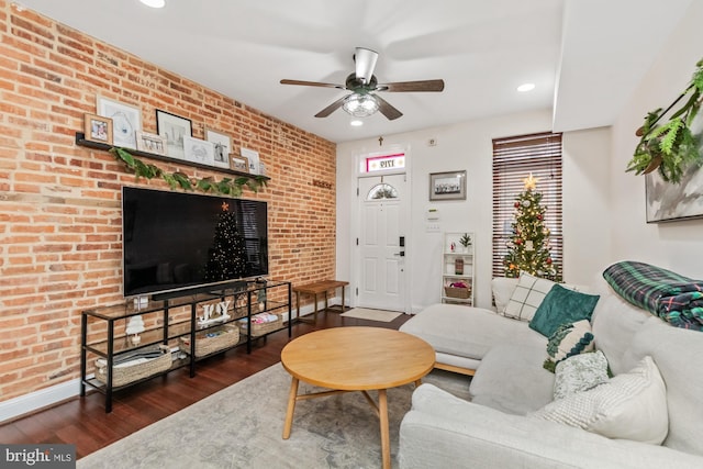 living room with dark hardwood / wood-style floors, ceiling fan, and brick wall