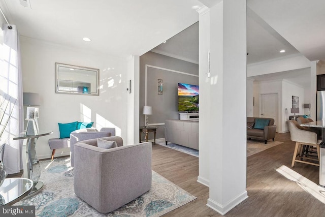 living room featuring crown molding, wood-type flooring, and decorative columns