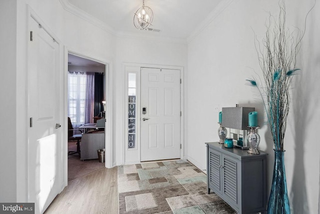 foyer featuring a notable chandelier, light hardwood / wood-style flooring, and ornamental molding