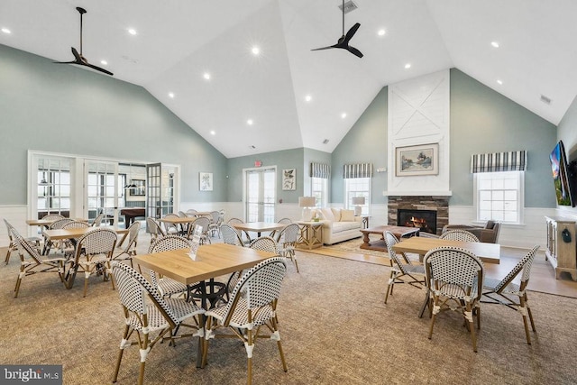 carpeted dining room featuring high vaulted ceiling, a healthy amount of sunlight, and ceiling fan