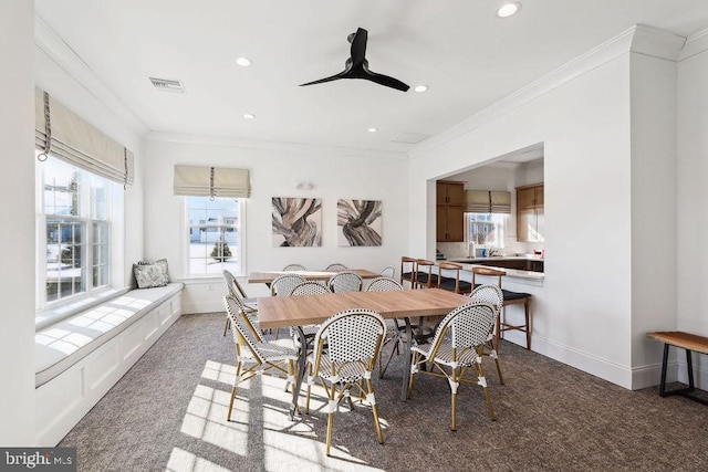 dining space with ceiling fan, ornamental molding, and dark carpet