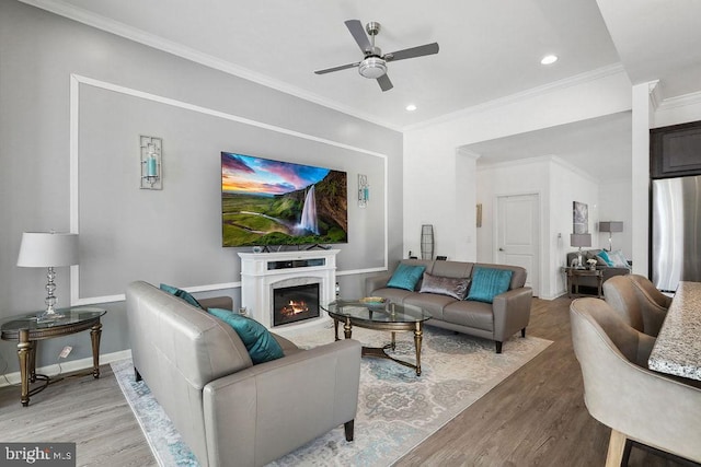 living room with crown molding, a high end fireplace, wood-type flooring, and ceiling fan