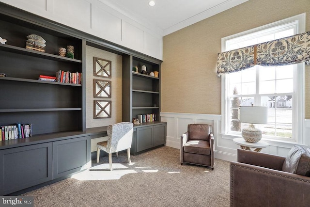 sitting room with built in shelves, light colored carpet, and crown molding