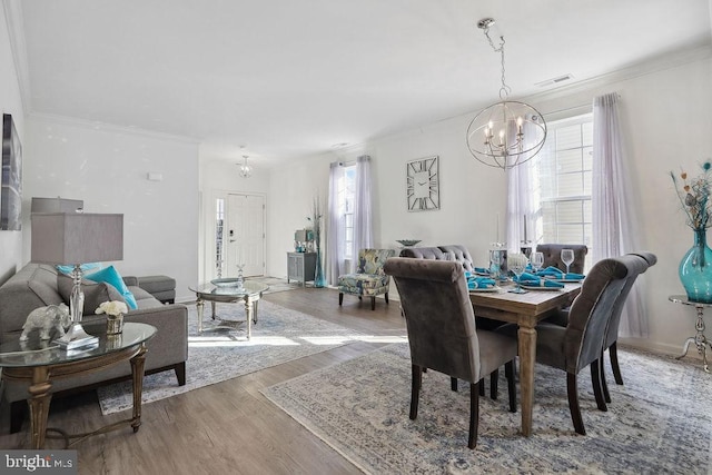 dining space featuring wood-type flooring, a notable chandelier, and crown molding