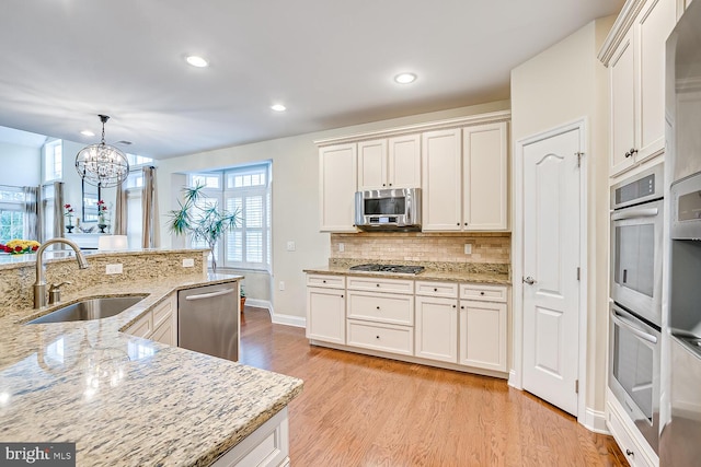 kitchen with pendant lighting, white cabinetry, appliances with stainless steel finishes, and sink