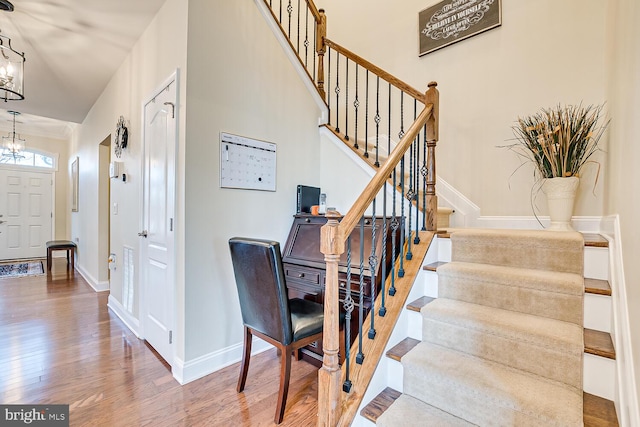 stairway with wood-type flooring and an inviting chandelier