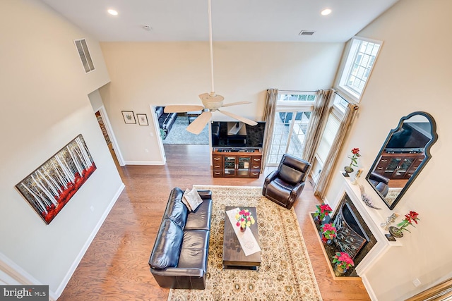 living room featuring hardwood / wood-style floors, ceiling fan, and a high ceiling