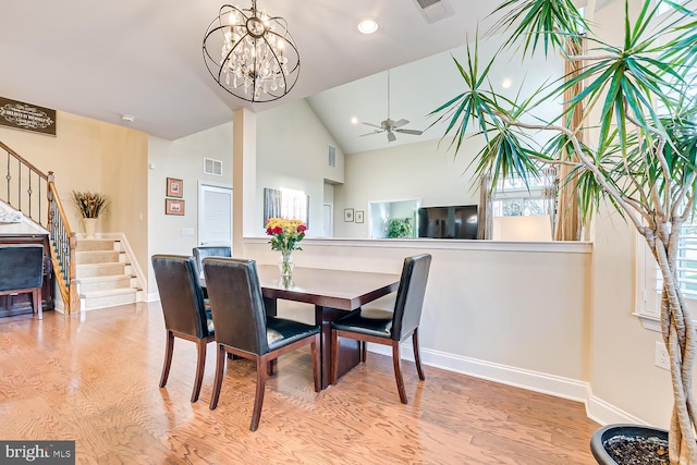 dining area featuring ceiling fan with notable chandelier, light hardwood / wood-style floors, and high vaulted ceiling