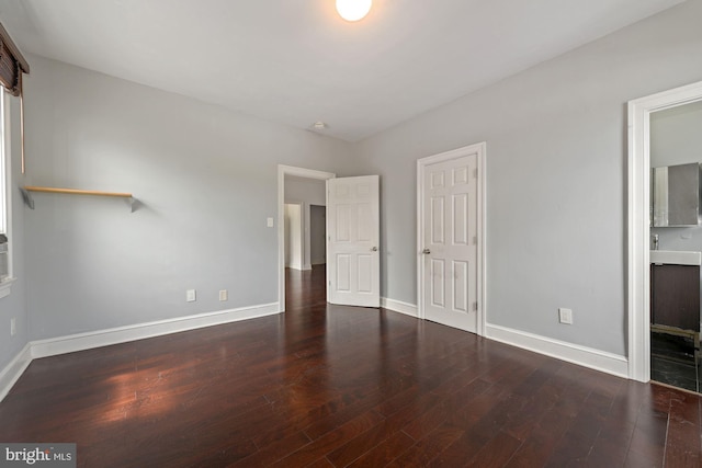 unfurnished bedroom with connected bathroom and dark hardwood / wood-style floors