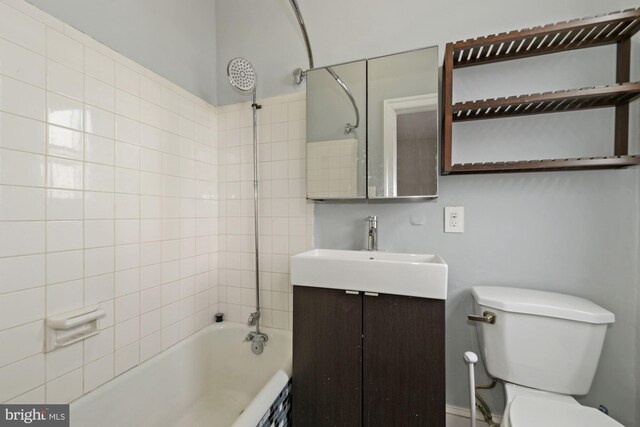 full bathroom featuring vanity, tiled shower / bath combo, and toilet