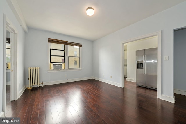 spare room with radiator, a wealth of natural light, and dark wood-type flooring